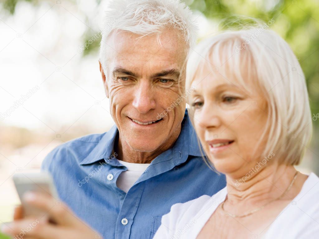 Happy senior couple looking at smartphone