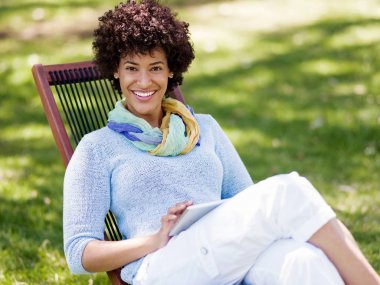 Parkta tablet kullanan genç bir kadın..