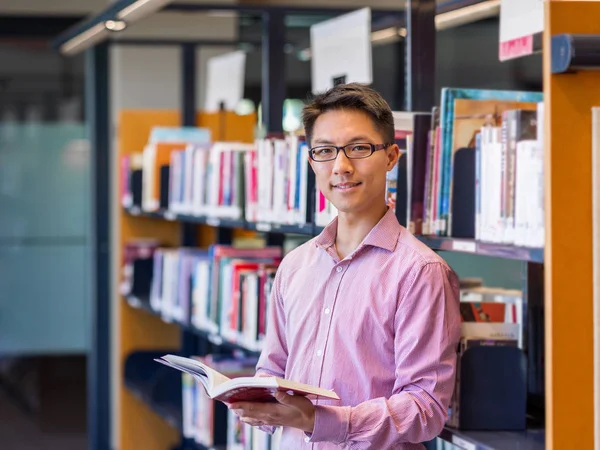 Szczęśliwy studentowi trzymania książek w bibliotece — Zdjęcie stockowe