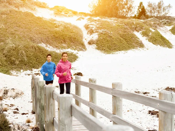 Pareja joven corriendo a lo largo de la orilla del mar — Foto de Stock