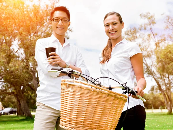 Πορτρέτο του χαμογελώντας ζευγάρι στέκεται στο πάρκο με ποδήλατο μιλάμε — Φωτογραφία Αρχείου
