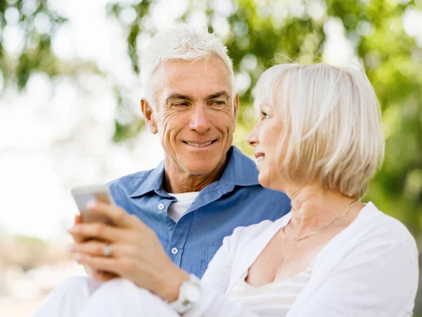 Щаслива старша пара дивиться на смартфон — стокове фото
