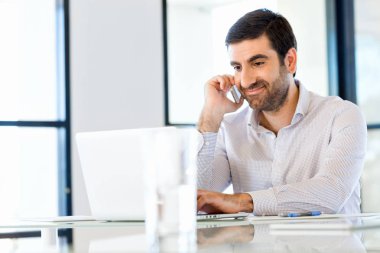 Kendine güvenen genç adam akıllı rahat kıyafet telefon tutarak