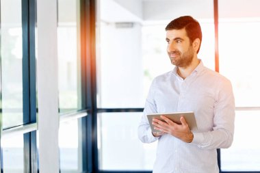 Genç yakışıklı işadamı onun touchpad ayakta kullanma office