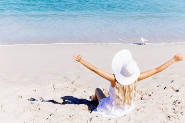 Genç bir kadın sahilde dinleniyor.