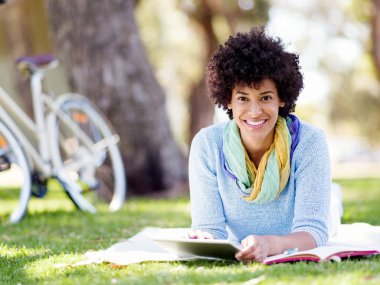 Parkta tablet kullanan genç bir kadın..