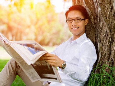 İş adamı parkta bir gazete okuyor