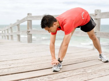 Genç adam sahilde egzersiz yaparak