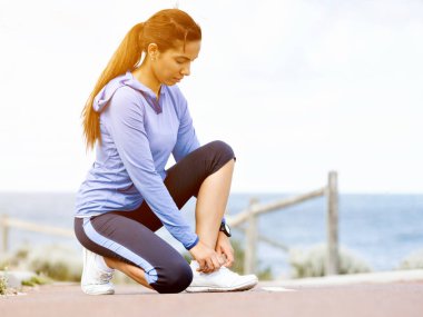 Kadın runner deniz kenarında bağcık bağlama