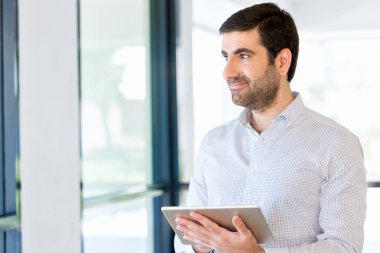 Genç yakışıklı işadamı onun touchpad ayakta kullanma office