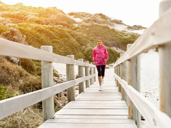 Mladá žena jogging na pláži — Stock fotografie