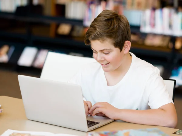 Ragazzo adolescente con tablet in biblioteca — Foto Stock