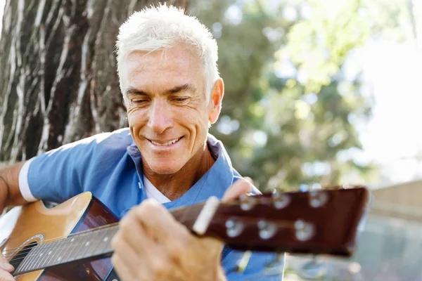 Uomo anziano che suona la chitarra all'aperto — Foto Stock
