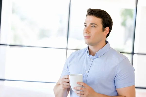 Joven hombre de negocios en la oficina con una taza —  Fotos de Stock