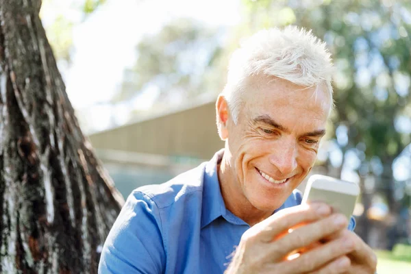 LoMature homme à l'extérieur en utilisant un téléphone mobile — Photo