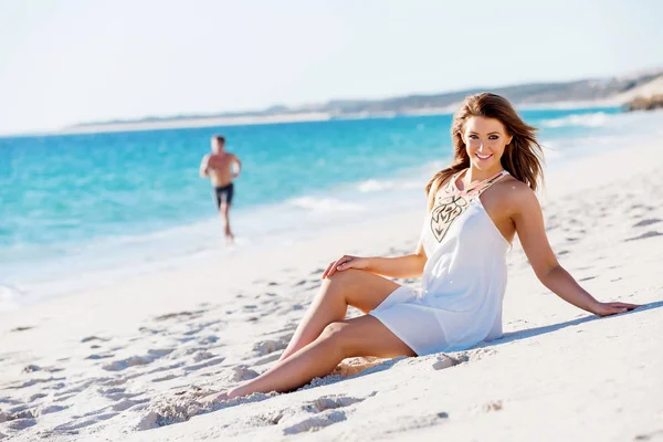 Młoda kobieta siedząca na plaży — Zdjęcie stockowe
