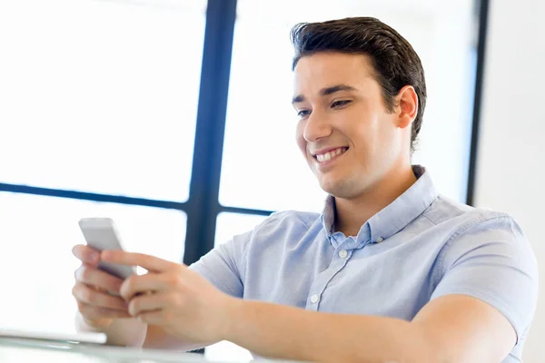 Självsäker ung man i smart fritidskläder som håller telefonen — Stockfoto