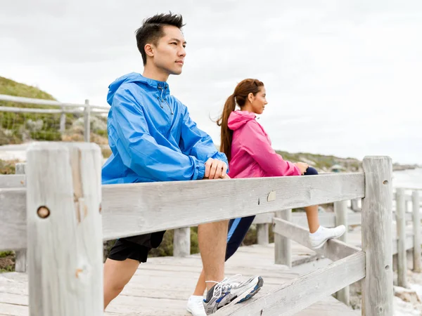 Young couple at the seaside doing exercises — Stock Photo, Image