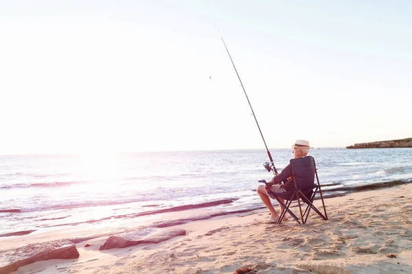 Senior mand fiskeri på havet side - Stock-foto
