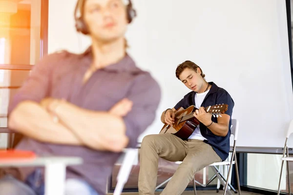 Jovem tocando guitarra no escritório — Fotografia de Stock