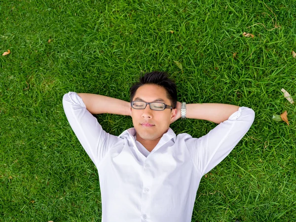 Ppretty young man in white shirt relaxing on a grass — Stock Photo, Image