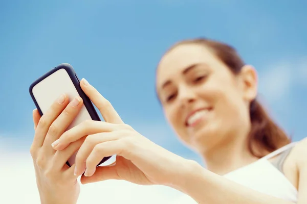 Female runner with her mobile smart phone standing outdoors — Stock Photo, Image
