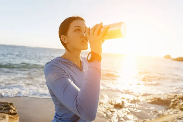 Mujer bebiendo agua en la playa — Foto de Stock