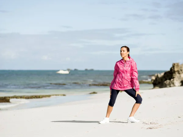 Jovem mulher na praia fazendo exercícios — Fotografia de Stock