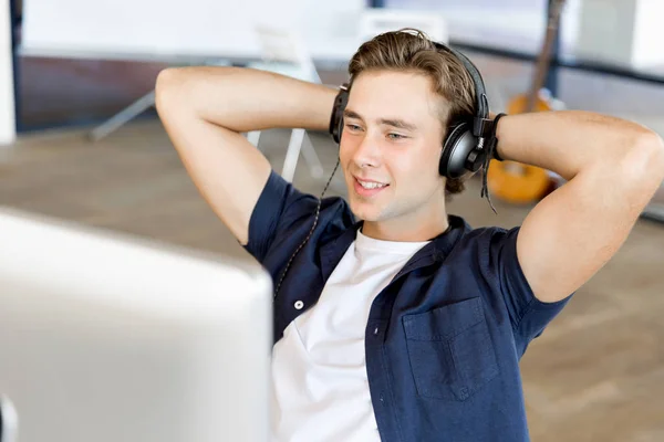 Jeune homme dans le bureau avec écouteurs — Photo