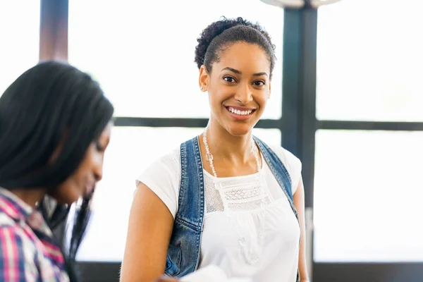 Portrait of smiling afro-american office worker in offfice with her colleague — Stock Photo, Image