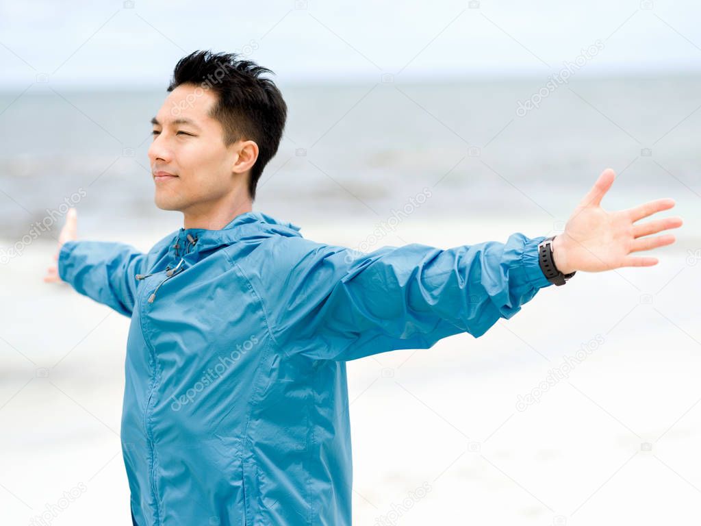 Young man with outstretched arms at the beach