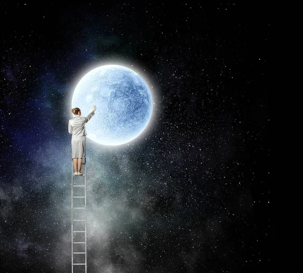 Affärskvinna på stege når månen — Stockfoto