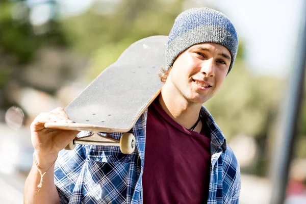 Adolescente com skate de pé ao ar livre — Fotografia de Stock