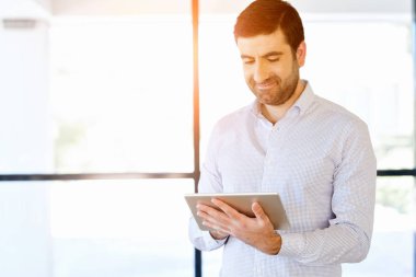 Genç yakışıklı işadamı onun touchpad ayakta kullanma office