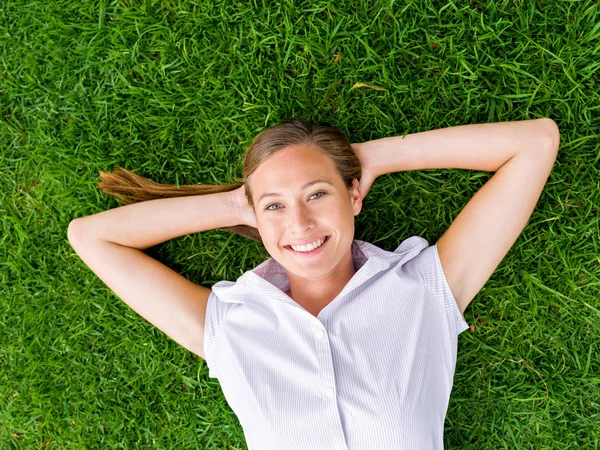 Mujer joven y bonita relajándose en una hierba — Foto de Stock