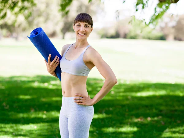 Junge Frau auf einer Turnmatte im Park — Stockfoto