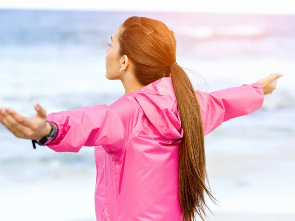 Молода жінка в спортивному одязі, що стоїть біля моря — стокове фото