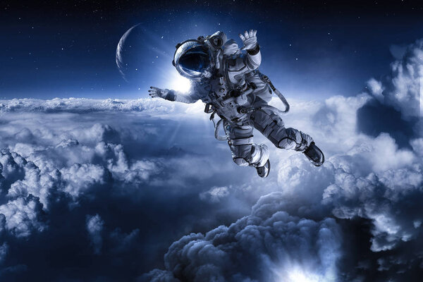 Astronaut in space above clouds of Earth . Elements of this image are furnished by NASA