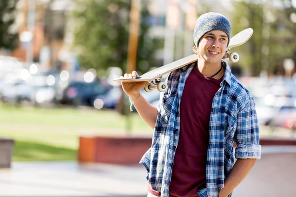 Adolescente con monopatín de pie al aire libre — Foto de Stock