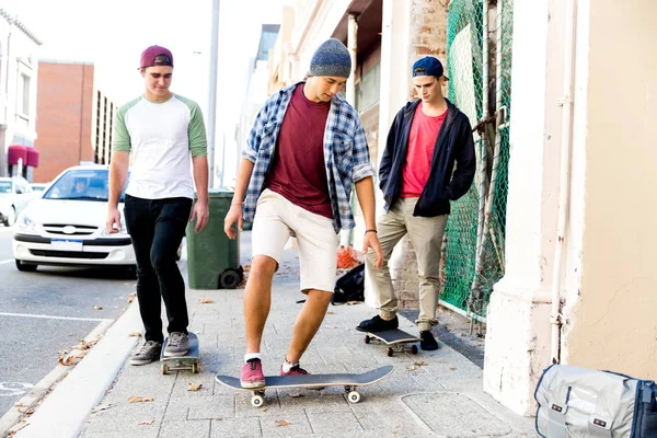 Amici adolescenti che camminano per strada con gli skateboard — Foto Stock