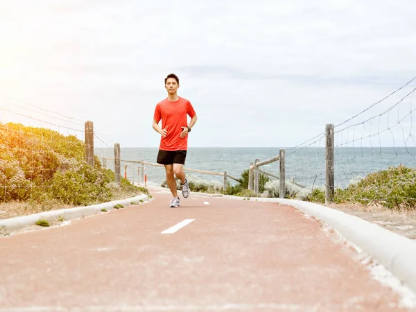 Νεαρός άνδρας τρέχει κατά μήκος ακτή — Φωτογραφία Αρχείου