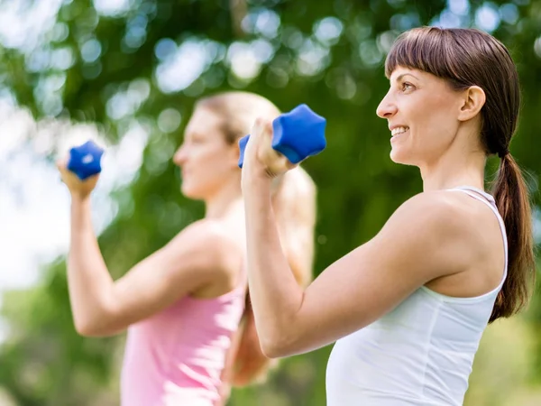 Portrait of cheerful women in fitness wear exercising with dumbbell — Stock Photo, Image