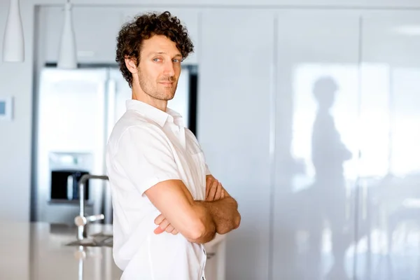 Retrato de um jovem inteligente em pé na cozinha — Fotografia de Stock