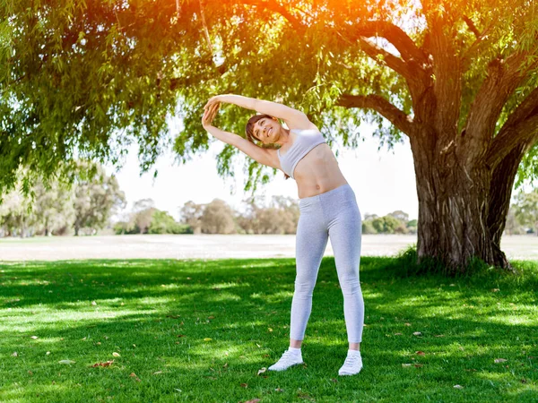 Parkta egzersiz yapan genç bir kadın. — Stok fotoğraf