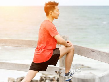 Genç adam sahilde egzersiz yaparak