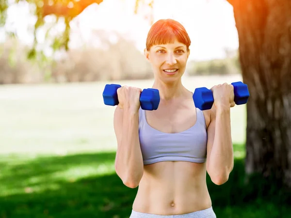 Portret van vrolijke vrouw bij de uitoefening van fitness slijtage met dumbbell — Stockfoto