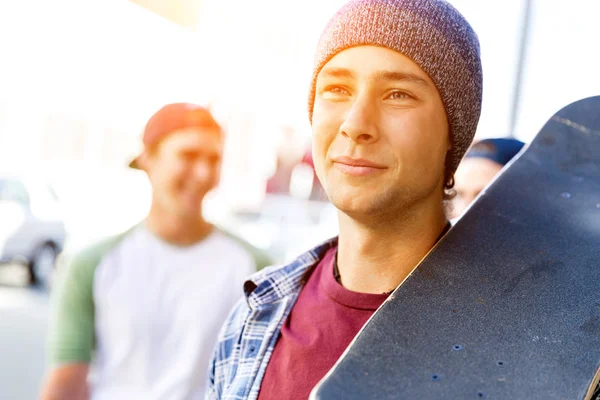 Tonåring pojke walking på gatan med sin skateboard — Stockfoto