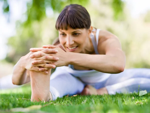 Giovane donna che pratica yoga nel parco — Foto Stock