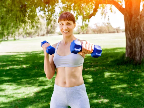 Portret van vrolijke vrouw bij de uitoefening van fitness slijtage met dumbbell — Stockfoto