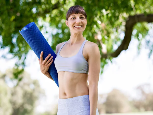 Junge Frau auf einer Turnmatte im Park — Stockfoto